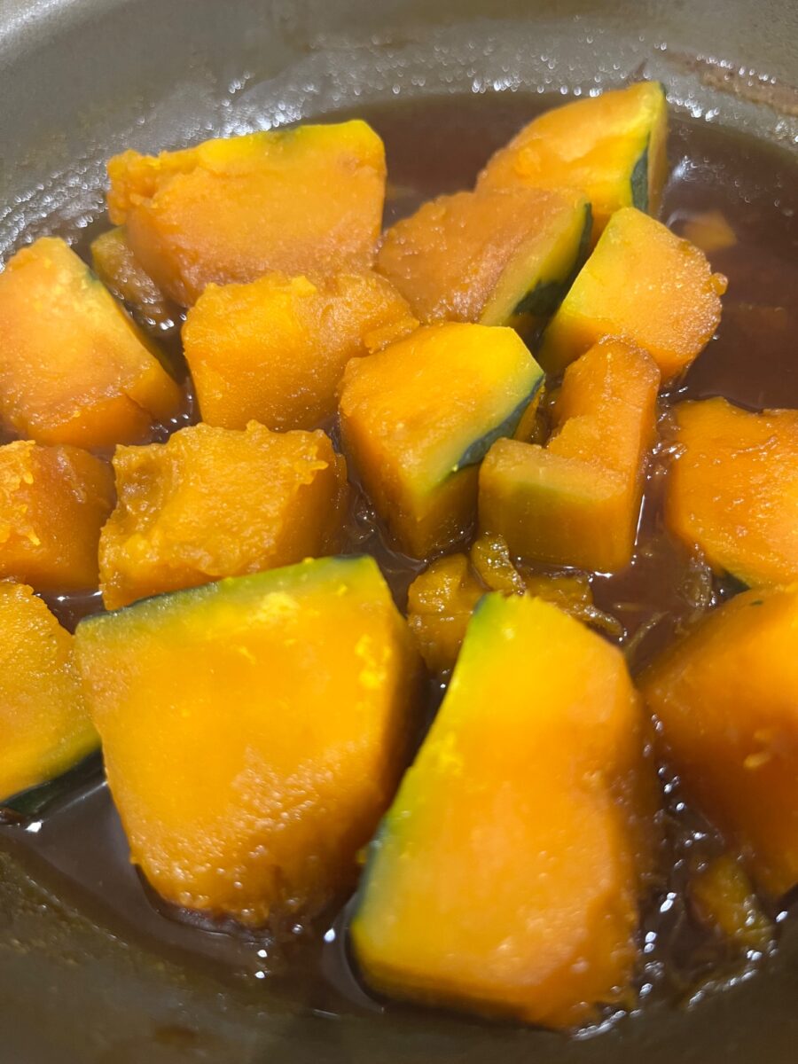 出汁が染みたかぼちゃの煮物のアップ・鮮やかなオレンジと緑の皮のコントラスト