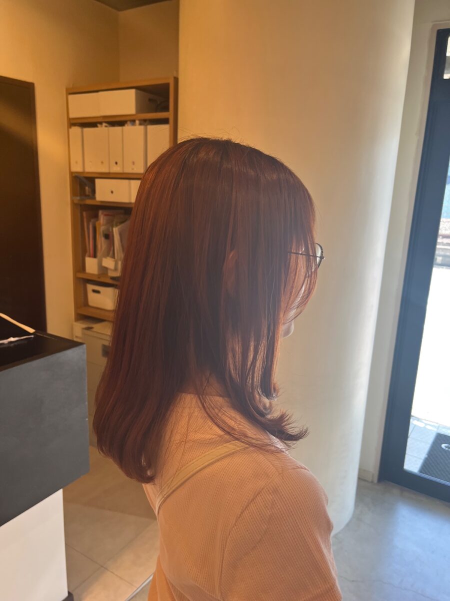 オレンジブラウンのアプリコットカラーで仕上げたミディアムヘア後ろ姿