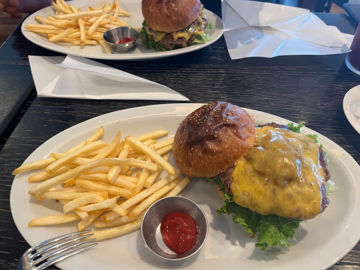 白い皿に盛るチーズバーガーとフライドポテト、ケチャップ添え