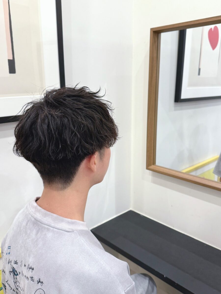 後ろ姿で見せる黒髪メンズパーマ、襟足すっきりフェードスタイル